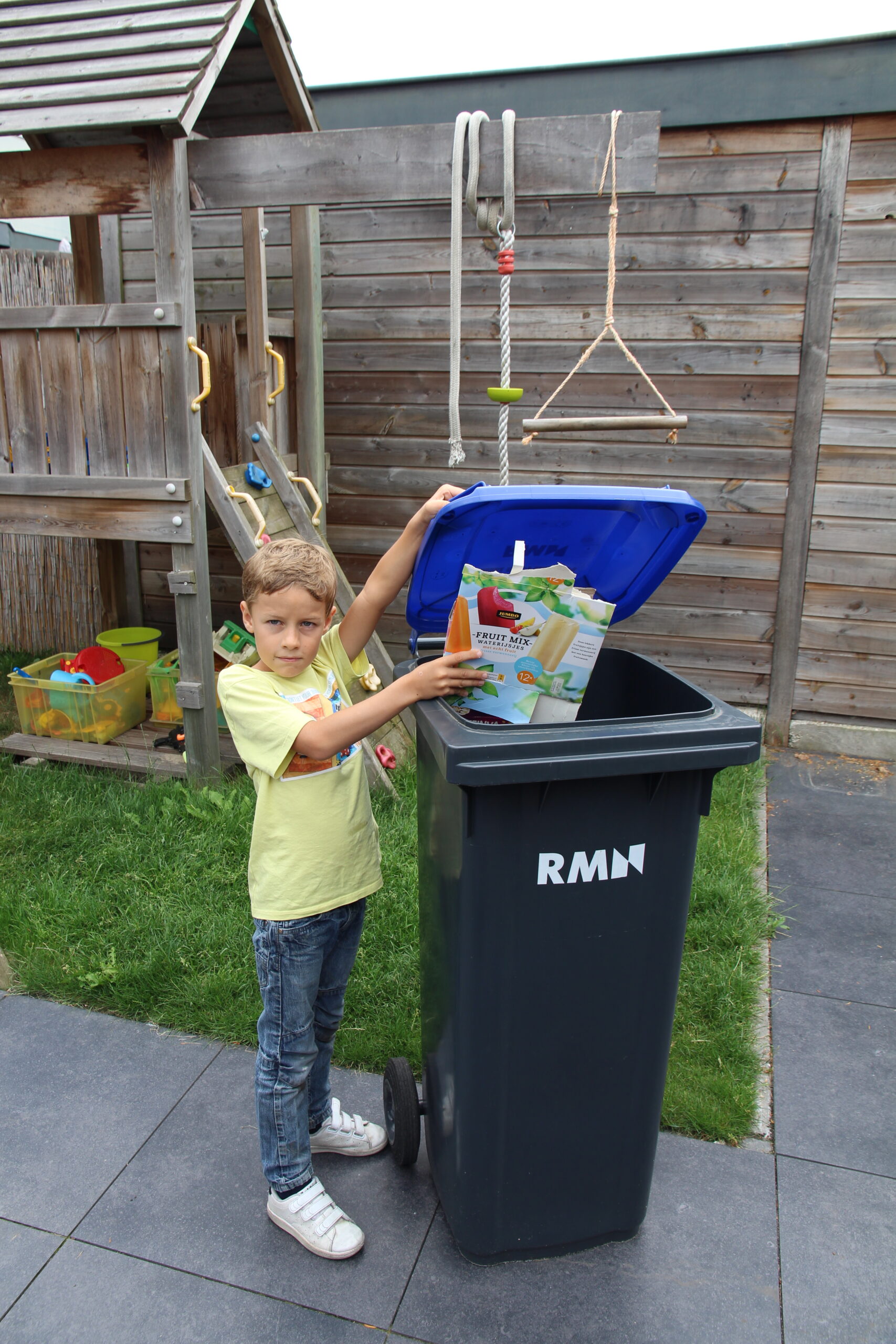 Foto van een jongetje dat papier in de papierkliko gooit
